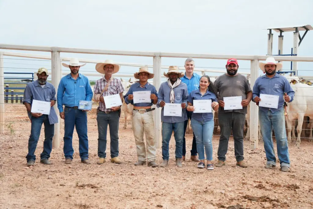 Colaboradores da Fazenda Boa Esperança, do Grupo Comaxim, exibem os certificados do treinamento de Lida Racional ao lado da equipe da Currais Itabira, no curral da fazenda